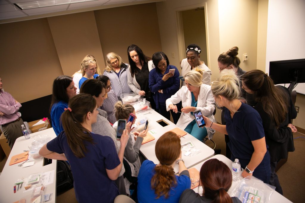 Graduate nursing students watch as a professor demonstates